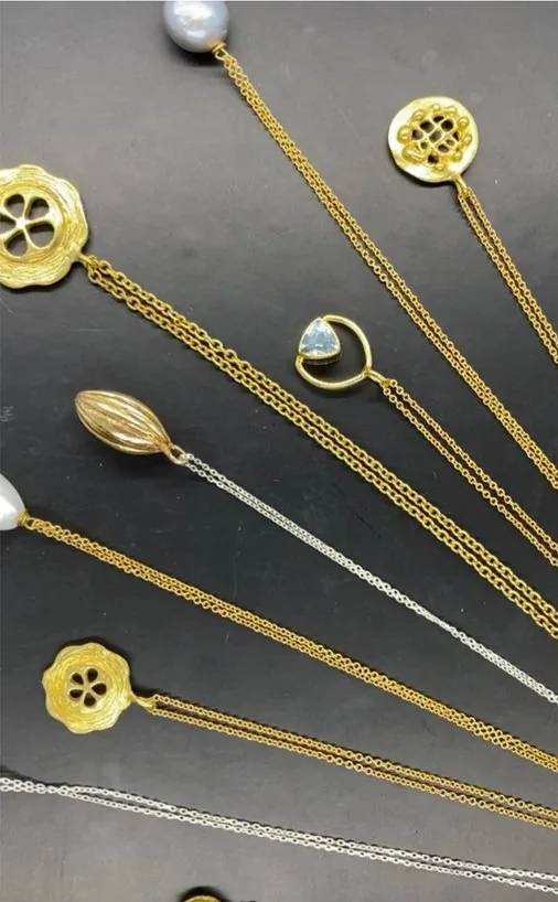 Ocean inspired gold pendants laid out on black like shells