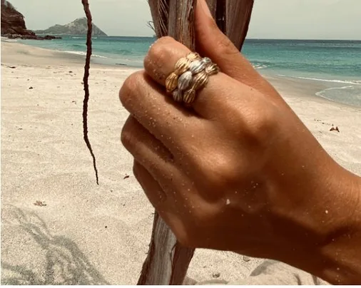 Ocean rings, stacked rings on a hand holding driftwood on a St Lucia beach