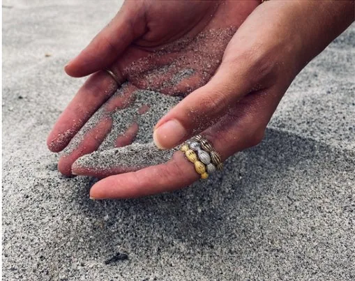 Ocean rings on hands sifting volcanic sand